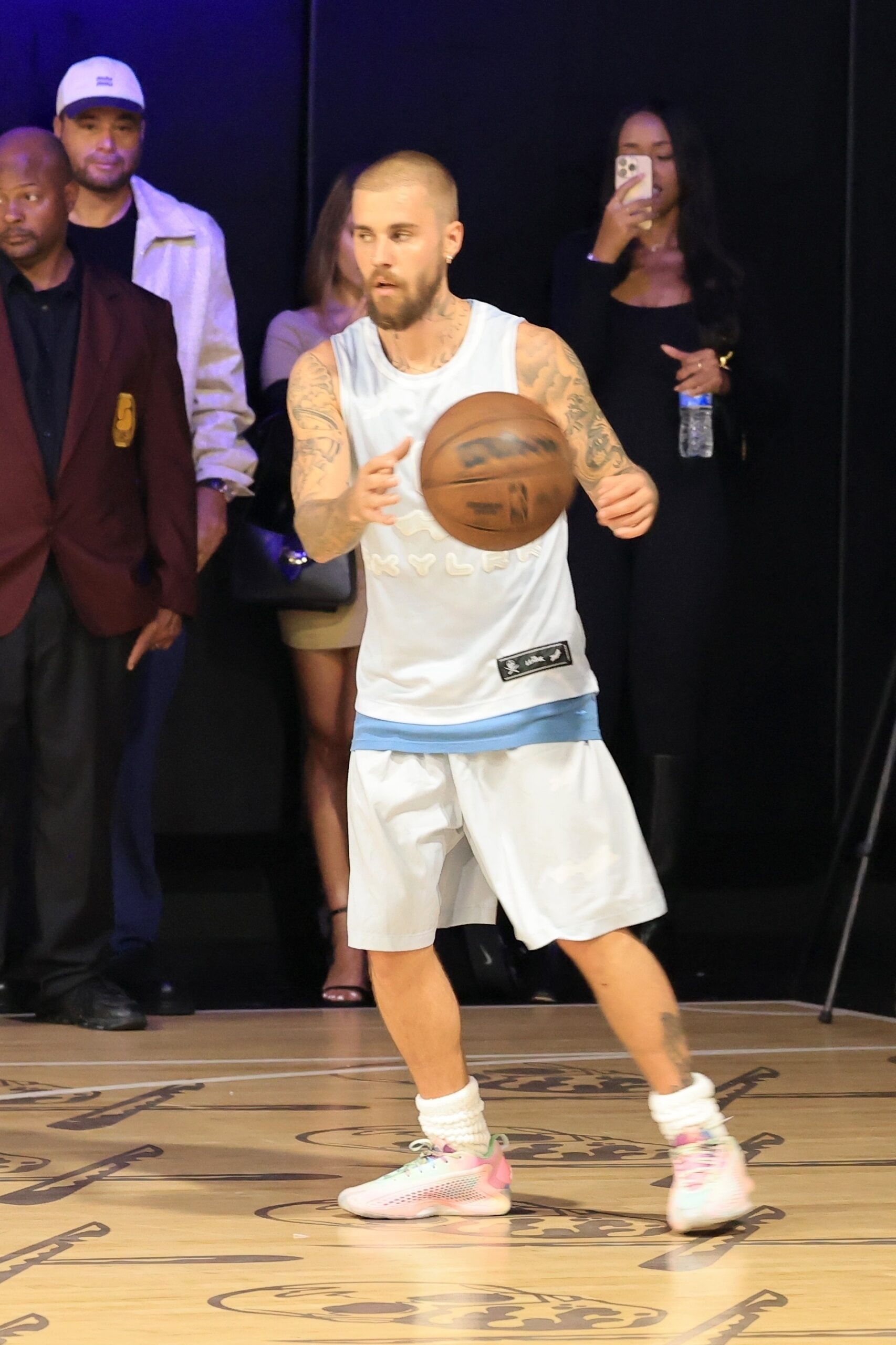 Justin Bieber playing basketball while wearing a black knee brace on his left leg.