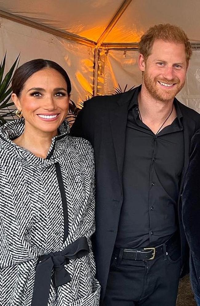 Meghan Markle in a black and white herringbone coat with a black sash and Prince Harry in a black shirt and blazer.