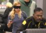 Addison Rae leaves LAX wearing an eye mask and casual travel clothes while rolling a suitcase. Photo: Backgrid.