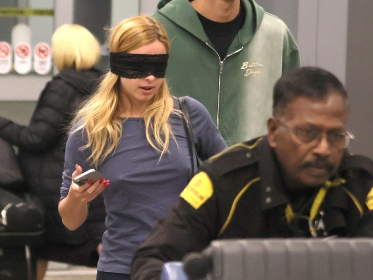 Addison Rae leaves LAX wearing an eye mask and casual travel clothes while rolling a suitcase. Photo: Backgrid.
